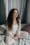 A serene woman meditates indoors on a bed, embodying tranquility and mindfulness.